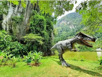 a statue of a dinosaur standing in the grass at The Haven 3 rooms residence Ipoh in Ipoh