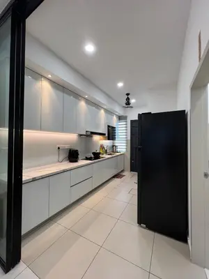 a kitchen with white cabinets and a black refrigerator at Cozy Home Simpang Ampat in Simpang Ampat