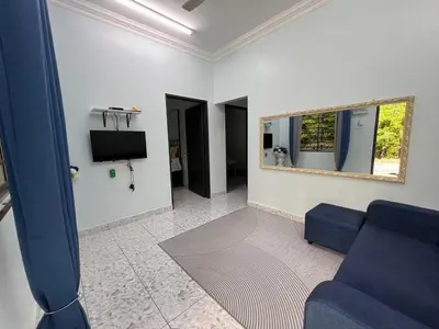 a living room with a blue couch and a mirror at Leman's Homestay in Balik Pulau