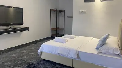 a bedroom with a bed and a flat screen tv at Capital O 91205 Palong Hill Chalet & Resort in Baling