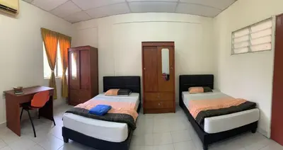 a bedroom with two beds and a table and a desk at Railway Hostel in Batu Gajah