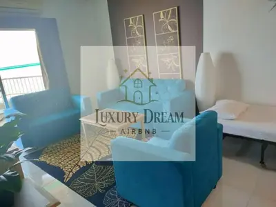 a living room with a blue couch and a table at Luxury Dream Seaview in Tanjung Bungah