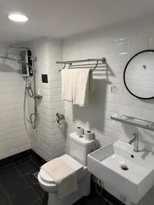 a white bathroom with a toilet and a sink at Embassy Hotel Georgetown in George Town