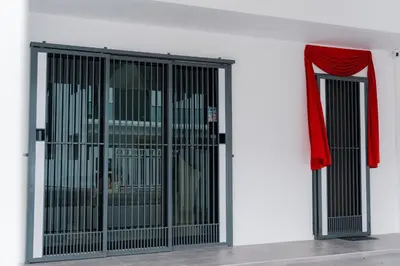 a cage with a red curtain on a white wall at SpaciousFun4BR Home 9Pax 3Bath Snooker ALMA in Bukit Mertajam