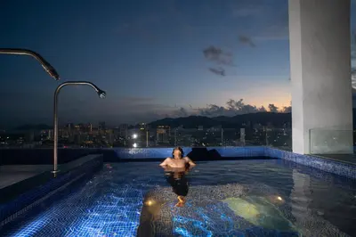 a woman in a swimming pool on top of a building at 22 Macalisterz Leisure Suites George Town in George Town