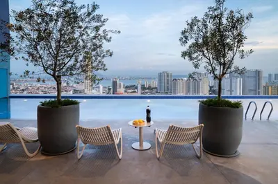 a rooftop patio with chairs and a table and trees at 22 Macalisterz Leisure Suites George Town in George Town