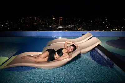 a woman is laying on an inflatable pool raft in a swimming pool at 22 Macalisterz George Town By KLIQ in George Town