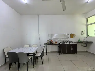 a room with a table and chairs and a kitchen at Padang Serai Wangi Homestay 402 in Padang Serai