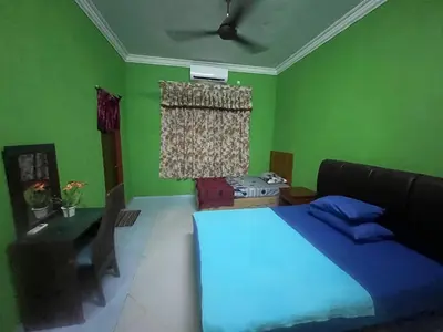 a green bedroom with a bed and a couch at Capital O 91206 Homestay Pelangi Ban Pecah. (muslim Only)