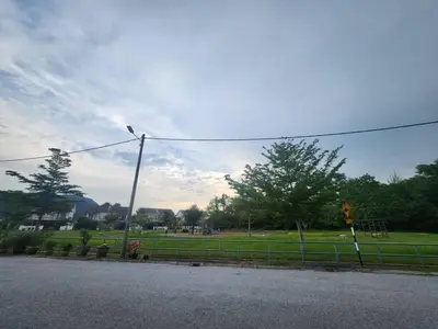 a street with a fence and a field with trees at Ipoh Seri Botani 5br22 pax bbq mahjong in Kampong Kepayang