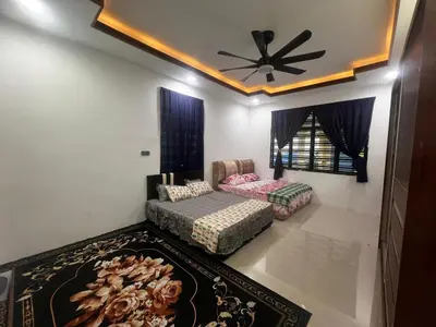 a living room with two beds and a ceiling fan at MY LENA Villa in Baling