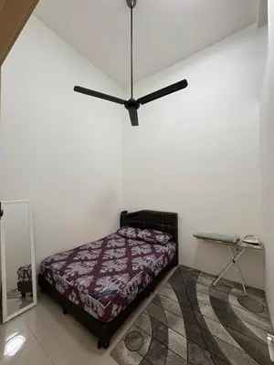 a bedroom with a bed and a ceiling fan at Homestay AtinAya in Tanjung Rambutan