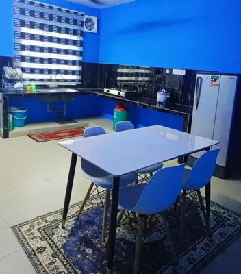 a blue kitchen with a white table and blue chairs at The Batrisyia Homestay in TanjongMalim