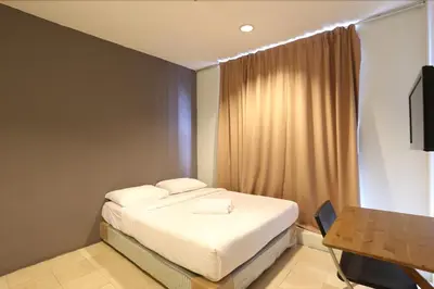 a bedroom with a bed and a desk and a television at NewTaunsHotel in Gua Sai