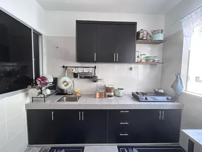 a kitchen with black cabinets and a sink at Homestay Rumah Raban in Kampong Kuala Chegar