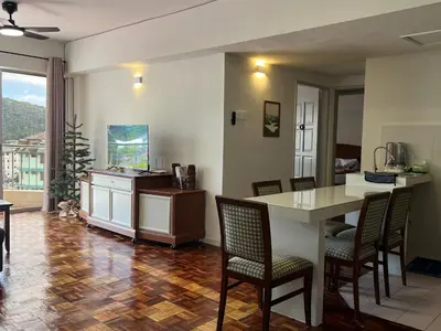a living room with a table and chairs and a kitchen at Moriash Stay in Brinchang