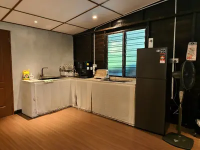 a kitchen with a table and a refrigerator at Rumah Atuk Homestay in Gua Musang