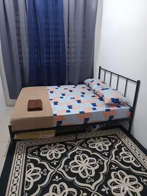 a bed in a room with blue curtains and a rug at FH Homestay Kuala Lipis 3R2B in Kuala Lipis