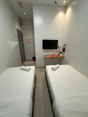 two white beds in a room with a tv at LM Motel in Kulim