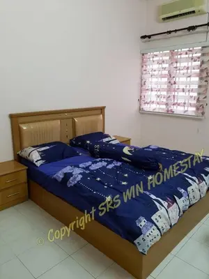 a bedroom with a bed with a blue comforter and a window at SRS WIN Homestay BPJ in Sungai Petani