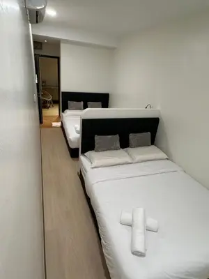 two beds in a room with white sheets at LM Homestay in Kulim