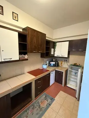 a kitchen with wooden cabinets and a counter top at Cameron Prima Villa Homestay in Tanah Rata