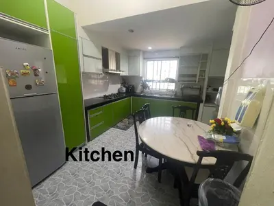 a kitchen with a table and a kitchen with green at ZzHomestay