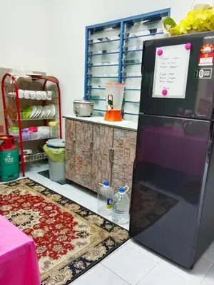 a kitchen with a refrigerator in front of a counter at Homestay Kak Kiah Taiping in Taiping
