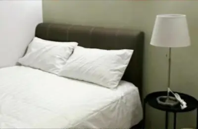 a bed with white sheets and pillows next to a lamp at Gracious Green Gurney in George Town