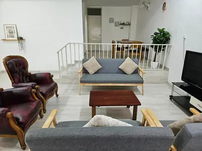 a living room with a couch and chairs and a tv at Leisure Homestay in Nibung Tebal