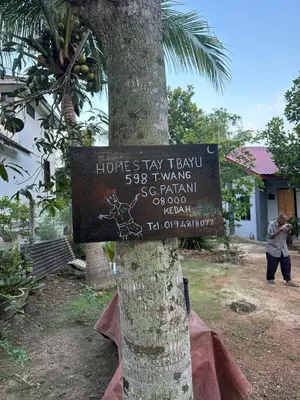 a sign on a tree in front of a building at Homestay Teluk Bayu in Sungai Petani