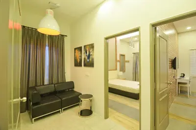 a living room with a black couch and a bed at Parkview Homes in Ipoh