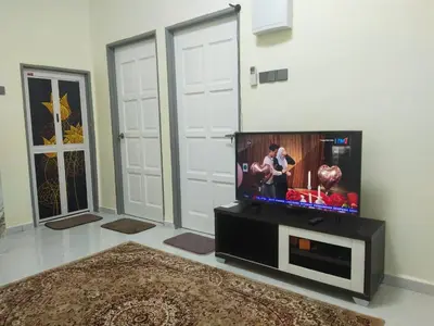 a living room with a flat screen tv sitting on a stand at Teratak Desa Cemerlang 2 in Kuala Kangsar