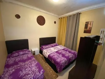two beds in a room with purple sheets at Crown Imperial Court - Arsad Homestay Brinchang in Brinchang