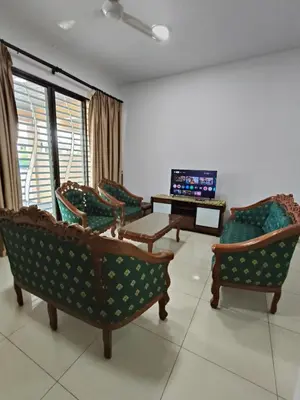 a living room with chairs and a table and a television at Bertam Wawasan Homestay in Kepala Batas