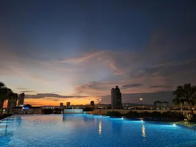 a large swimming pool with a city skyline at night at Metropol by BRB in Bukit Mertajam