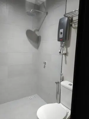 a white bathroom with a toilet and a tv on the wall at Urban Inn Kulim in Kulim