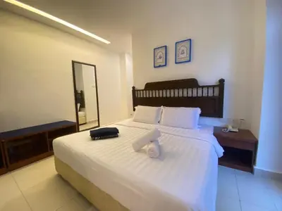 a bedroom with a white bed with a mirror at Mak Sa'adiah Hotel in Kampung Teluk Nipah