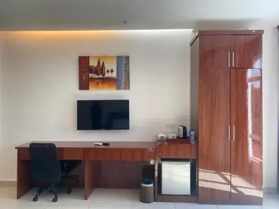 a room with a desk with a television and a cabinet at Mak Sa'adiah Hotel in Kampung Teluk Nipah