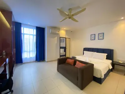 a bedroom with a bed and a couch and a ceiling fan at Mak Sa'adiah Hotel in Kampung Teluk Nipah