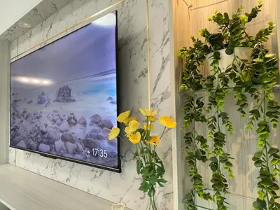 a television hanging on a wall with flowers at NEW Bt Kawan8 3BR Suite-IKEA-UOW-KDU-ColumbiaAsia in Simpang Ampat