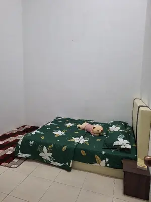 a bed with a green comforter with a stuffed animal on it at Rosselle Homestay, Sabak Bernam in Sabak Bernam