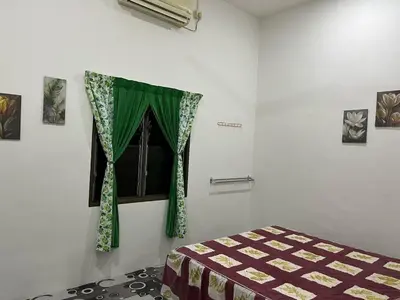 a bedroom with a window with a green curtain at Homestay ABAH in Nibung Tebal