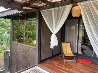 a porch of a house with a curtain and a chair at Rumah Inap Kampung Agong Sunrise in Penaga