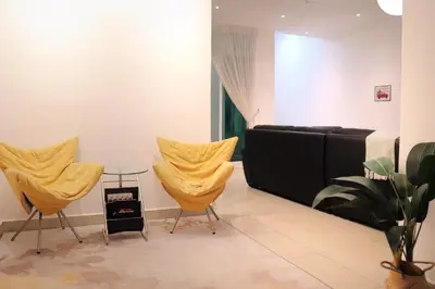 a room with two yellow chairs and a television at Alle House by Wei in Kampong Gurun