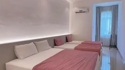 a room with two beds and a couch and a window at Alle House by Wei in Kampong Gurun