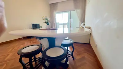 a white table with stools in a room with a window at Straits Quay Seaview in Tanjung Bungah
