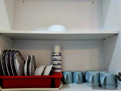 a shelf with plates and mugs in a kitchen at d01 The Anderson Ipoh Family Stay 2BR in Ipoh