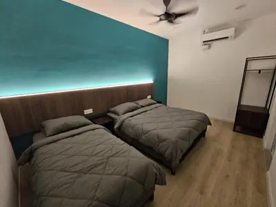 two beds in a room with a blue wall at Roomstay KOBANAS in Ipoh
