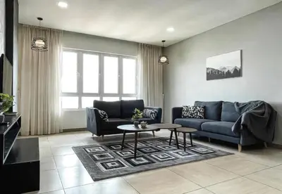a living room with a blue couch and a table at Jomstay Octagon Ipoh Penthouse in Ipoh